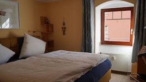 A bedroom with a bed, a window with curtains, a radiator, and a wall-mounted shelf with a small item. - Holiday apartment in Waren with swimming pool (Waren)