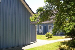 Un bâtiment à la façade bleue, un chemin pavé et une petite pelouse.