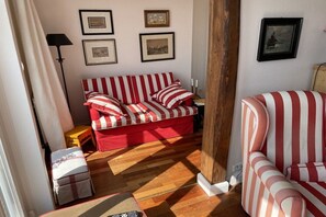 A room with a striped sofa, a small table, a lamp, and framed pictures on the wall. - Old Doctor's House 2 (Juist)