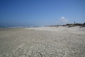 A wide sandy beach with dunes and a lighthouse in the distance. - Old Doctor's House 2 (Juist)