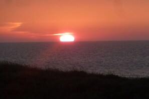 Un coucher de soleil sur une étendue d’eau, avec une ligne d’horizon.