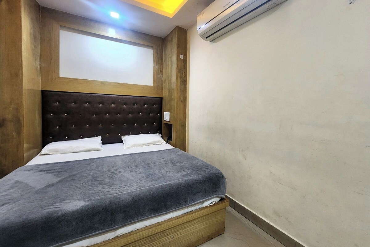 A bedroom with a bed, an air conditioning unit, and a ceiling light fixture.