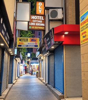A corridor with closed shops and a hotel sign for 'Hotel Cottage Lord Krishna' with a contact number. - Oly Hotel Cottage lord Krishna  (New Delhi)