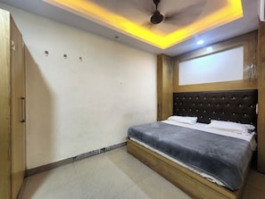 Un dormitorio con cama, ventilador de techo y armario de madera.