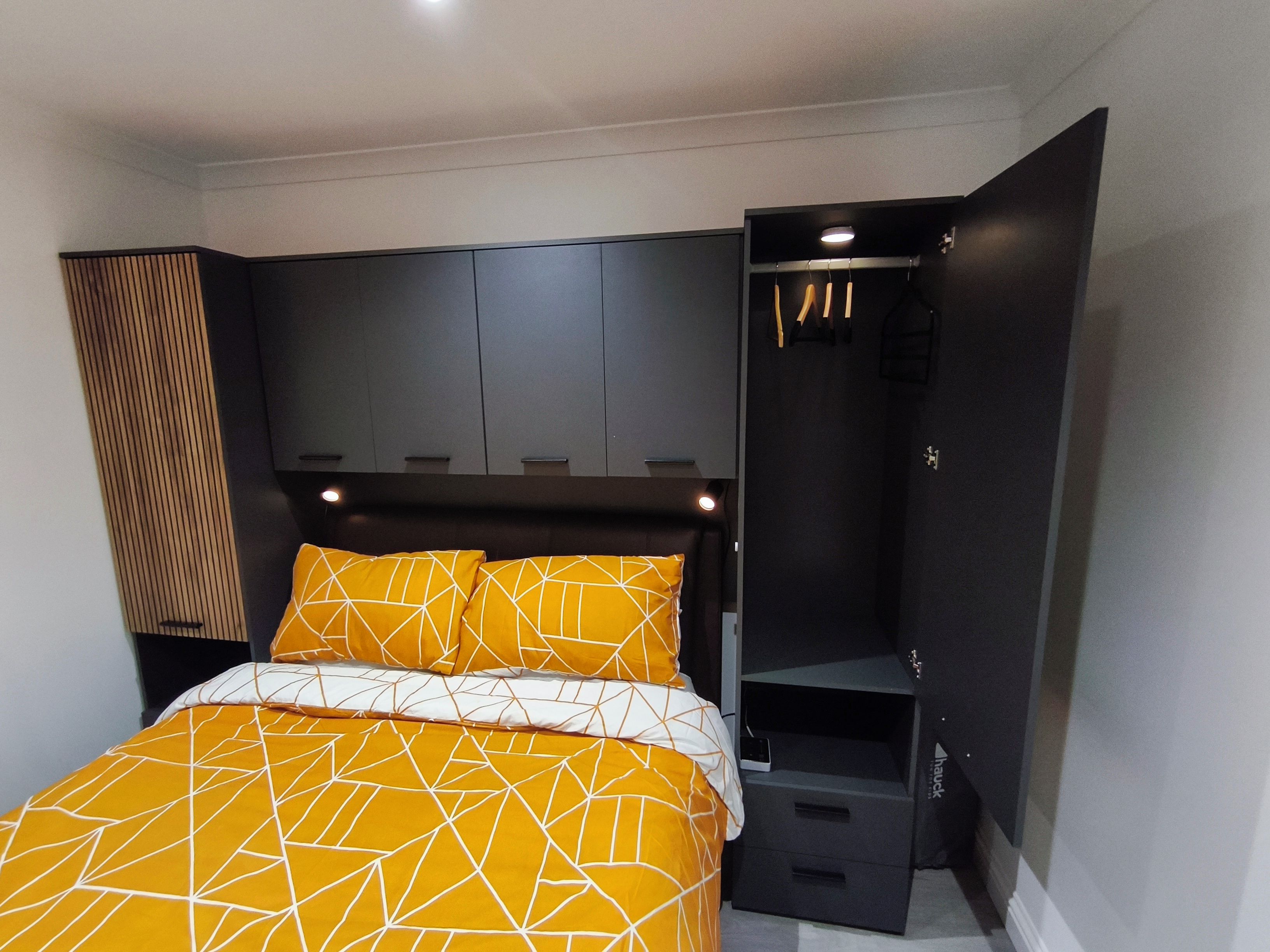 Une chambre à coucher comprenant un lit, une armoire et un banc intégré.