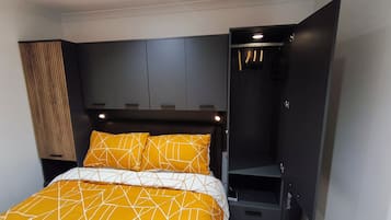Ein Schlafzimmer mit einem Bett, einem Kleiderschrank und einer eingebauten Sitzbank.