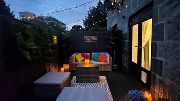 An outdoor patio area with a sofa, cushions, and a patterned rug.
