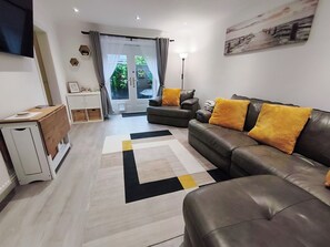 Un salon moderne avec un canapé, une table basse et un téléviseur à écran plat fixé au mur.