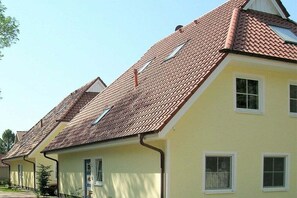 Una hilera de casas amarillas con tejados rojos y marcos de ventanas blancos.