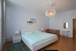 Ein Schlafzimmer mit einem Einzelbett, Nachttischen, einem Hängeleuchter und einem Spiegel.