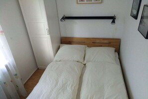 Ein Einzelbett mit Holz Kopfteil, ein Nachttisch und ein Wandregal.