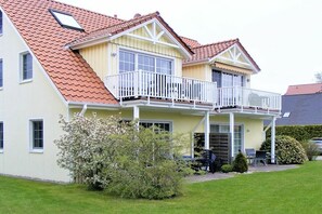 A two-story house with a red-tiled roof, a balcony, and a small garden area. - Buchengrund W 2 || Ostseebad Prerow (Ostseebad Prerow)