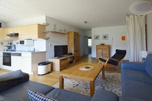 A modern living space with a kitchen, dining area, and seating. - Buchengrund W 2 || Ostseebad Prerow (Ostseebad Prerow)