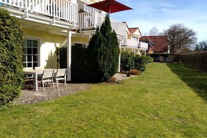 Ein Wohngebäude mit Balkon, Rasen und einem Tisch mit Stühlen.