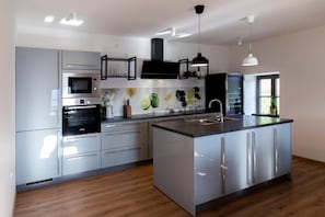 Una cocina moderna con electrodomésticos de acero inoxidable, una isla central e iluminación colgante.