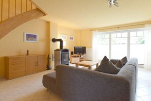 En stue med sofa, fjernsyn, træskab og pejs.