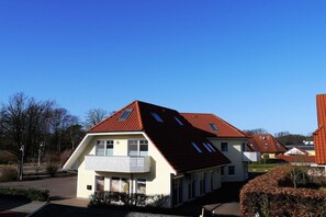Ein Wohngebäude mit geneigtem Dach und einem Balkon, bewölkter Himmel.