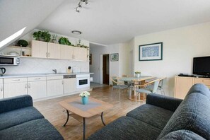 A modern living space with a kitchen, dining area, and seating area. - House "Am Brunnen" W.3 (Ostseebad Prerow)