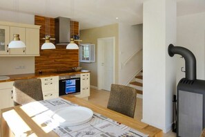 A modern kitchen with wooden cabinets, a built-in oven, and pendant lighting. - Holiday home Wiecker Landhus | FHH 2 (Wieck)