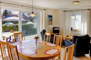 Ein Essbereich mit einem runden Tisch, Stühlen und einem Fernseher im Hintergrund.