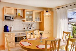 Eine Küche mit Holzausstattung, einer Mikrowelle, einem Backofen und einem Esstisch mit Stühlen.