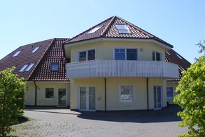 A two-story house with a balcony, a tiled roof, and a paved driveway. - House "Am Brunnen" Where 7 (Ostseebad Prerow)