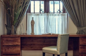 A wooden desk with a chair, a vase with dried plants, and a book. - Stafford Estate Bungalow (Nuwaraeliya)