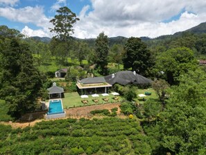 A property with a swimming pool, outdoor seating, and a view of the surrounding greenery and hills. - Stafford Estate Bungalow (Nuwaraeliya)