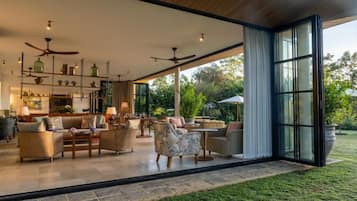 Un espacio interior amplio con un conjunto de asientos, una cocina con estantes, y un ventanal que ofrece vistas al exterior.