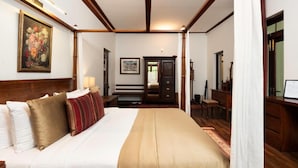 A hotel room with a large bed, a wooden headboard, a desk, and a chair. - Stafford Estate Bungalow (Nuwaraeliya)