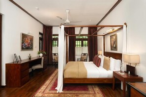 A four-poster bed with a canopy, a desk with a chair, a bedside table with a lamp, and a large window with curtains. - Stafford Estate Bungalow (Nuwaraeliya)