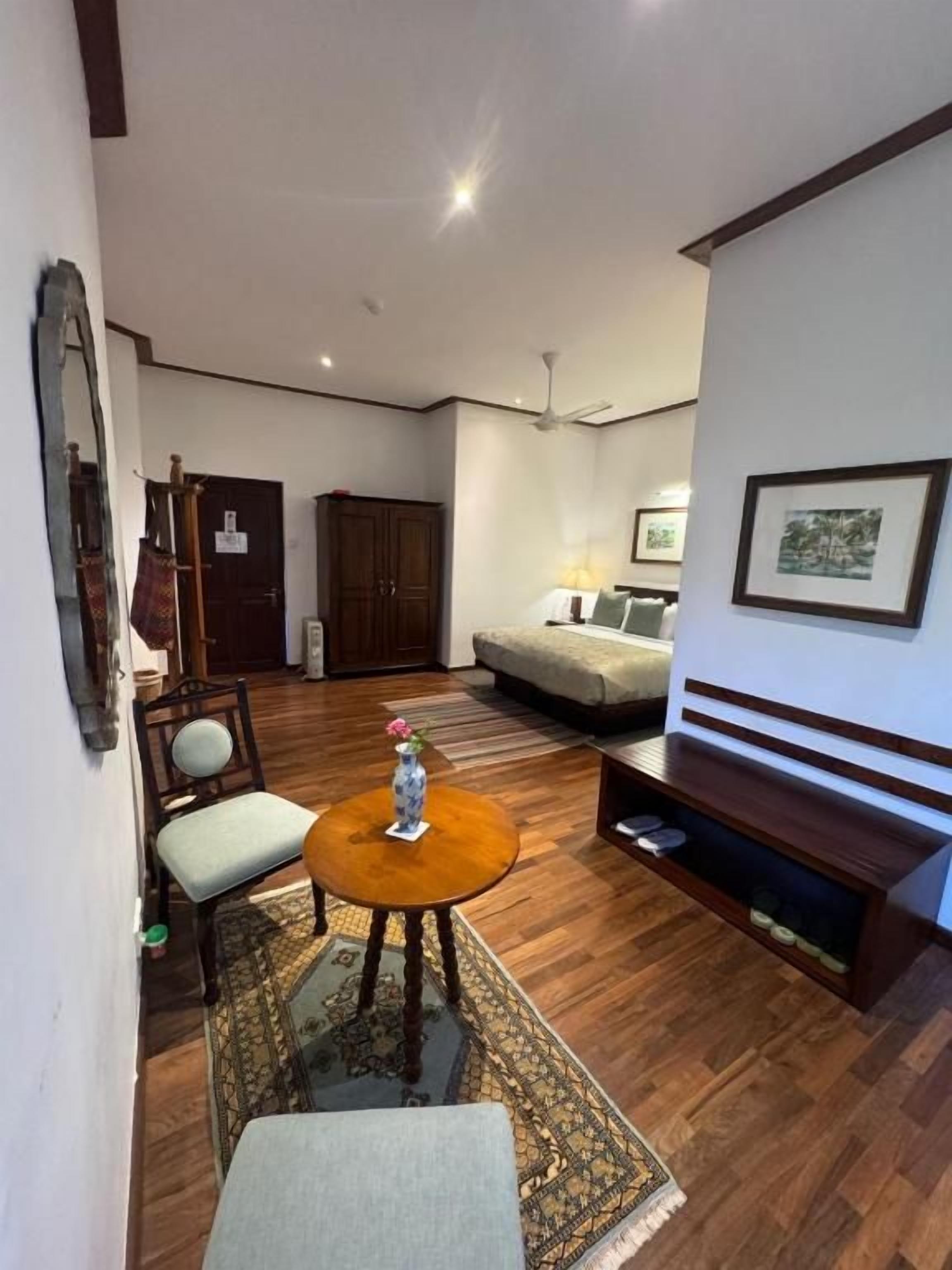 Una sala de estar con sofá, una mesa de centro, una silla, un mueble para televisión y un cuadro enmarcado en la pared.