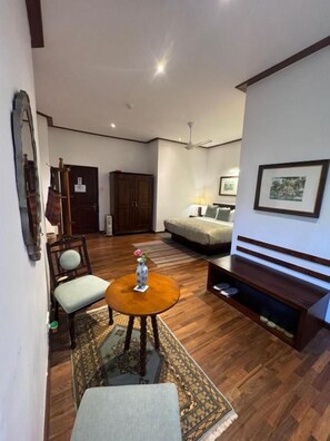 A living room with a sofa, a coffee table, a chair, a TV stand, and a framed picture on the wall.