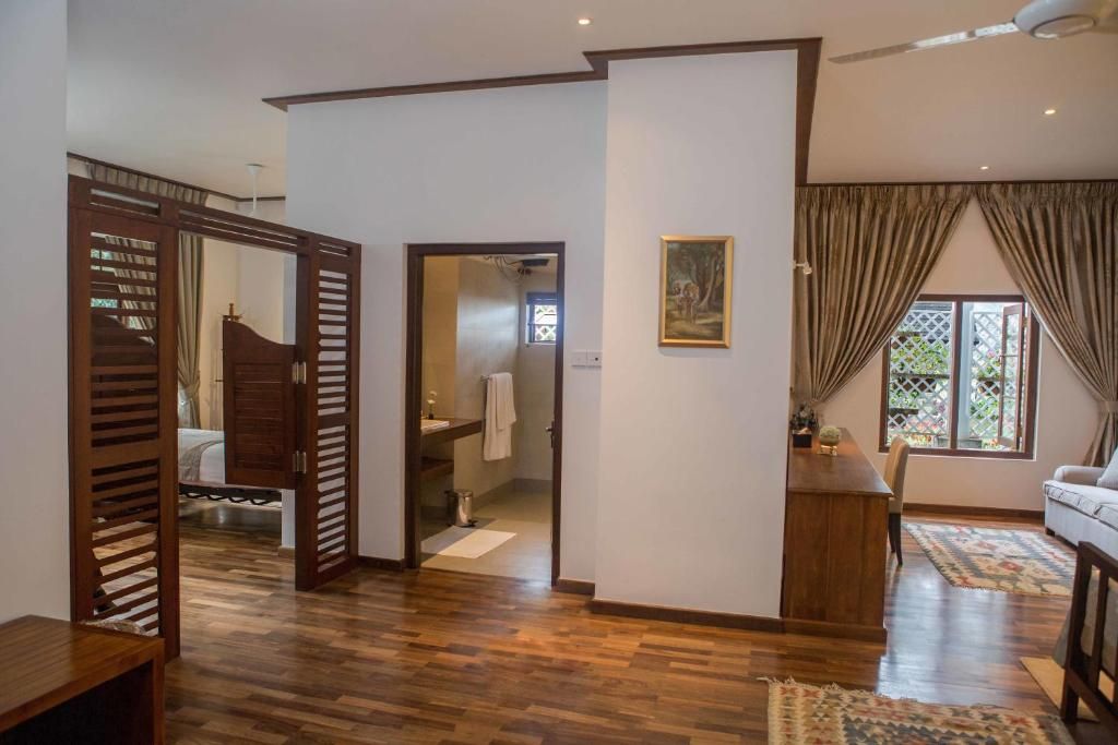 A room with a wooden floor, a bed, a desk, a chair, and a window with curtains.