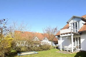Ein Wohnhaus mit weißer Fassade, einem roten Ziegeldach und einem kleinen Garten mit Trampolin.