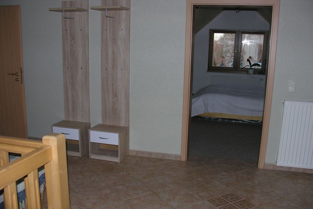 A bedroom with a bed, a window, a radiator, and a door.
