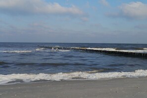 A beach with waves approaching a wooden pier. - Holiday apartment with 2 bedrooms (Prerow)