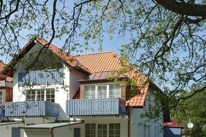 A two-story building with a red-tiled roof, balconies, and a clear sky. - Holiday apartment with 1 bedroom (Ostseebad Prerow)
