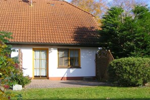 A single-story house with a tiled roof, a front door, and a small front yard with a hedge. - Terraced house with 2 bedrooms (Ostseebad Prerow)
