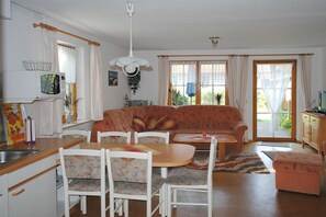 Uma sala de estar acolhedora com sofá, cadeiras, uma mesa de jantar e uma área de cozinha com micro-ondas.