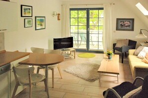 Ein Wohnzimmer mit Fernseher, einer Couch, einem Couchtisch und einem Essbereich mit Stühlen.