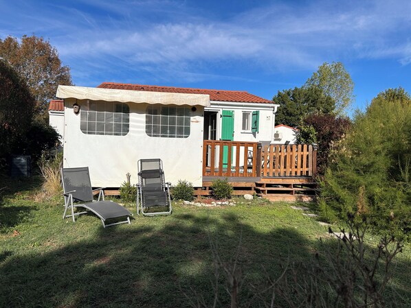 A mobile home with a patio area, including a chair and a sun lounger.