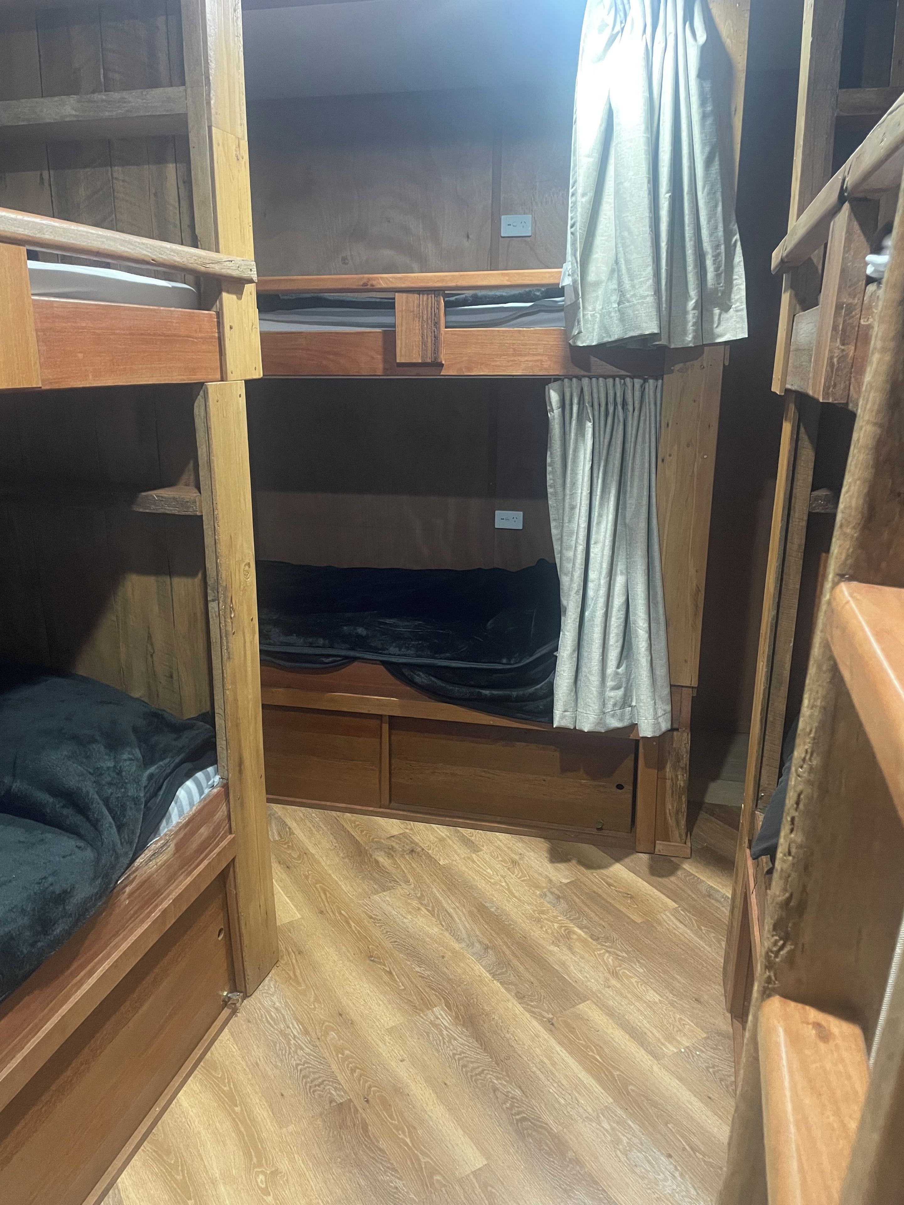 A bunk bed room with wooden flooring and a window.