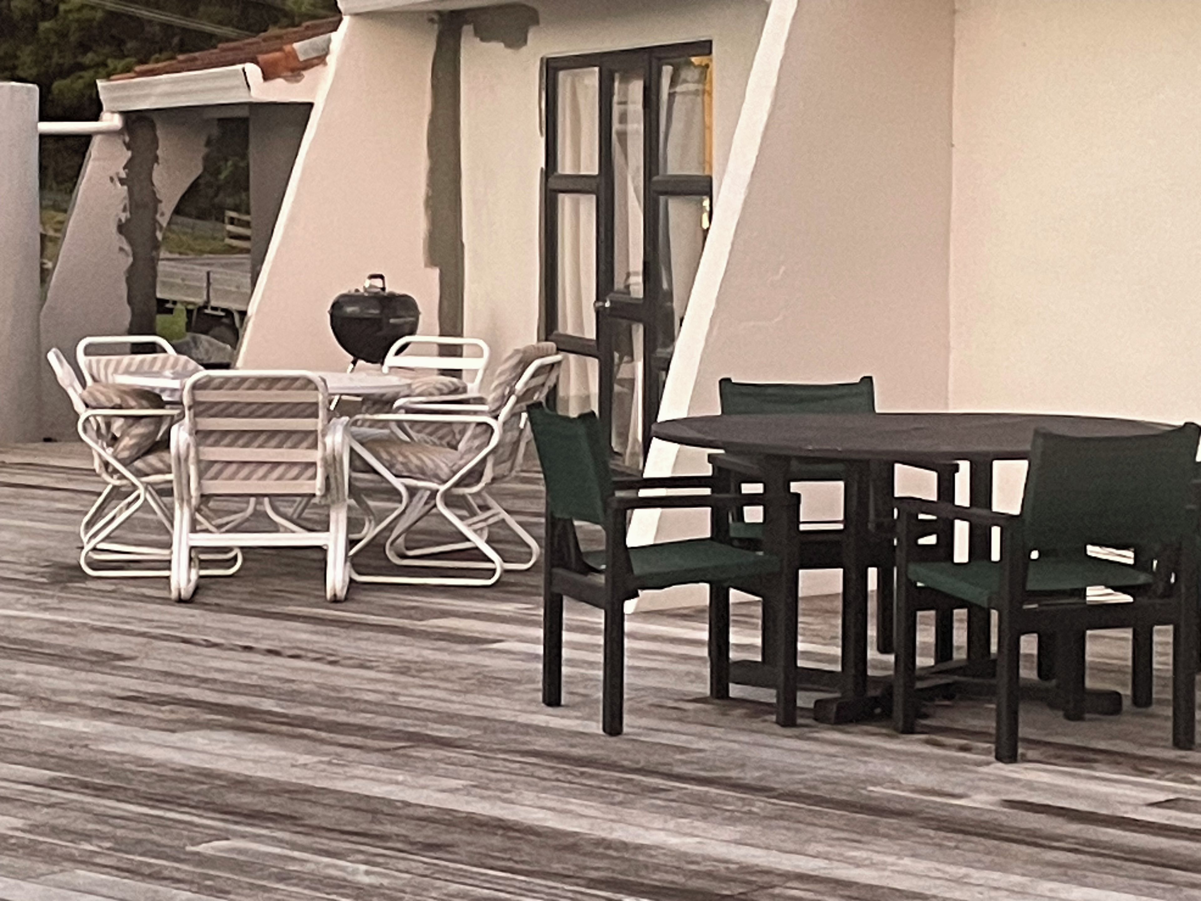 A patio with a table and chairs, a grill, and a view of the surrounding landscape.