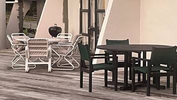 A patio with a table and chairs, a grill, and a view of the surrounding landscape.