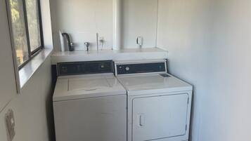 A laundry room with two stacked washers and dryers, a window, and a white wall.