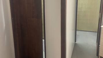 A hallway with a wooden door, a white wall, and a grey floor.