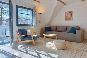 Ein gemütliches Wohnzimmer mit einer Couch, einem Sessel, einem Couchtisch und einer Stehlampe.