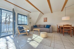 A spacious living area with a sofa, a chair, a small table, and a dining set. - Oak Park W 2.5 || Ostseebad Prerow (Ostseebad Prerow)