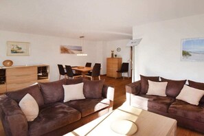 A modern living room with a sofa set, a dining table with chairs, and a cabinet. - Holiday home with 3 bedrooms (Ostseebad Prerow)